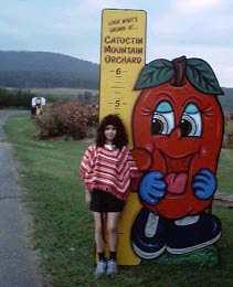 Miranda in front of a growth chart. She looks to be 4 foot-8.