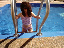 Miranda in her bathing suit getting climbing the ladder into the pool