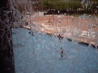 Children playing in a fountain from behind a waterfall.